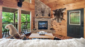 A cozy cabin interior with a stone fireplace, wooden walls, and a fur rug. - Bear Mountain Chalet in the Woods w/ Hot Tub (Sevierville)