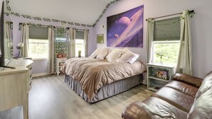 A bedroom with a bed, a desk, a dresser, a window with curtains, a wall with a space-themed painting, and a ceiling fan. - Calm Columbia Haven: Outdoor Pool, Hot Tub! (Blairstown)