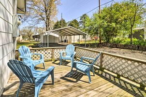 A wooden deck with blue Adirondack chairs and a covered patio area.