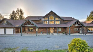 A two-story log cabin with a large central window and a garage on the left. - Brookings Vacation Rental Lodge on 88 Acres! (Brookings)