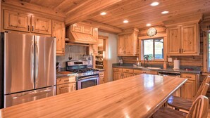 A spacious kitchen with wooden cabinets, stainless steel appliances, and a large island. - Brookings Vacation Rental Lodge on 88 Acres! (Brookings)
