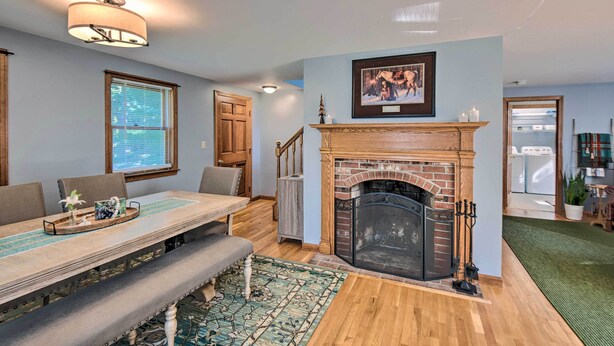 A dining area with a long table, benches, a fireplace, and a staircase leading to another room. - Charming Saco Home w/ Deck, 5 Mi to Beach! (Saco)