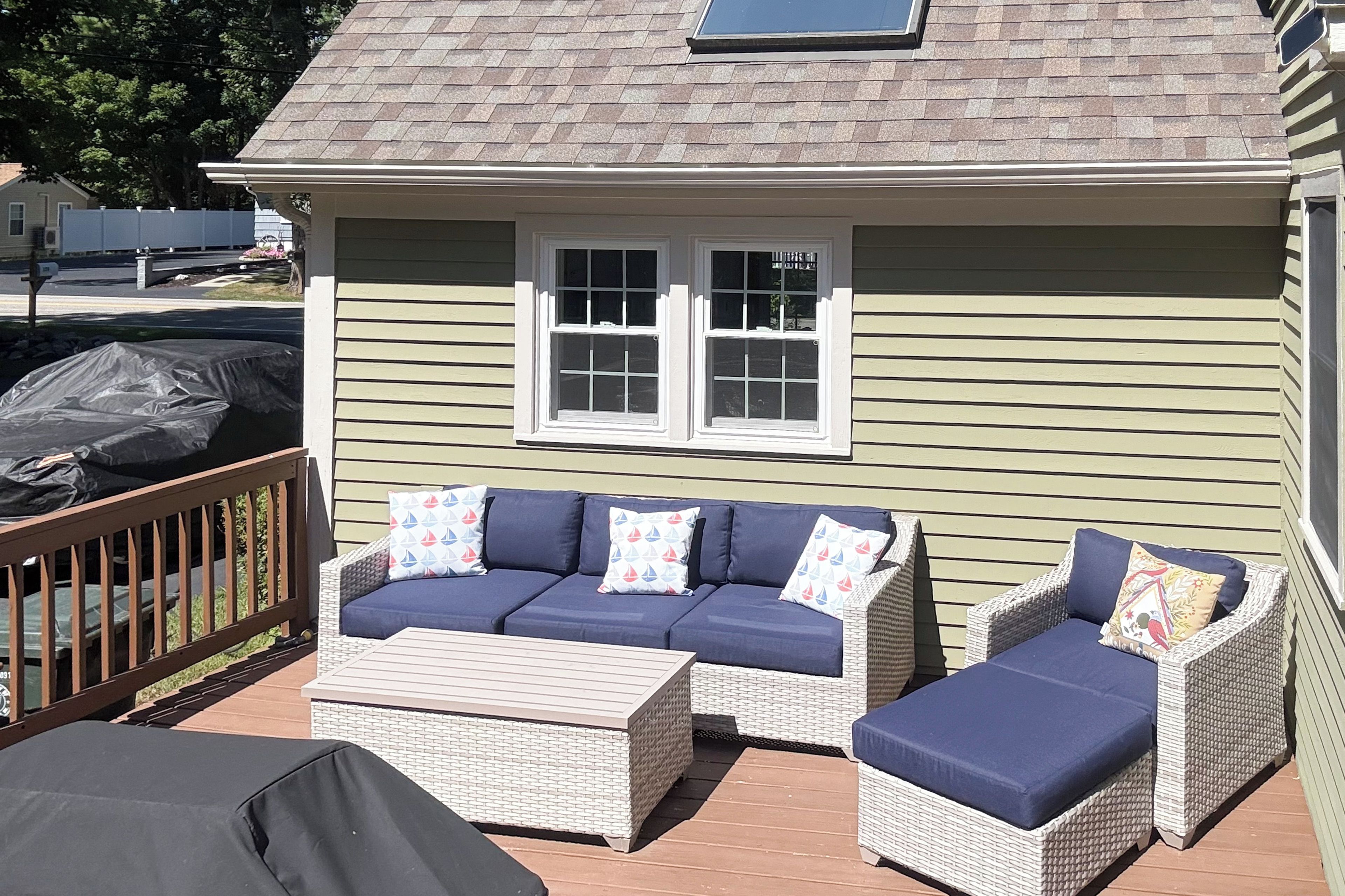 A covered outdoor seating area with a sofa and two chairs, a small table, and a window.