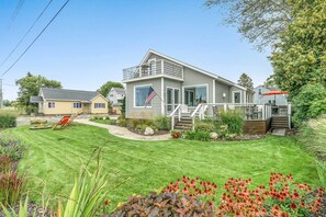 A two-story house with a front deck, a flag, and a well-maintained lawn. - Chic Manistee Cottage: Steps to Lake Michigan! (Manistee)