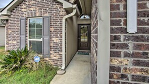 A brick house with a front door, a mailbox, and a small garden.