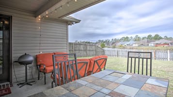 Enjoy al fresco dining on the patio, where a table and chairs await, accompanied by a barbecue grill and a side table with a lamp.