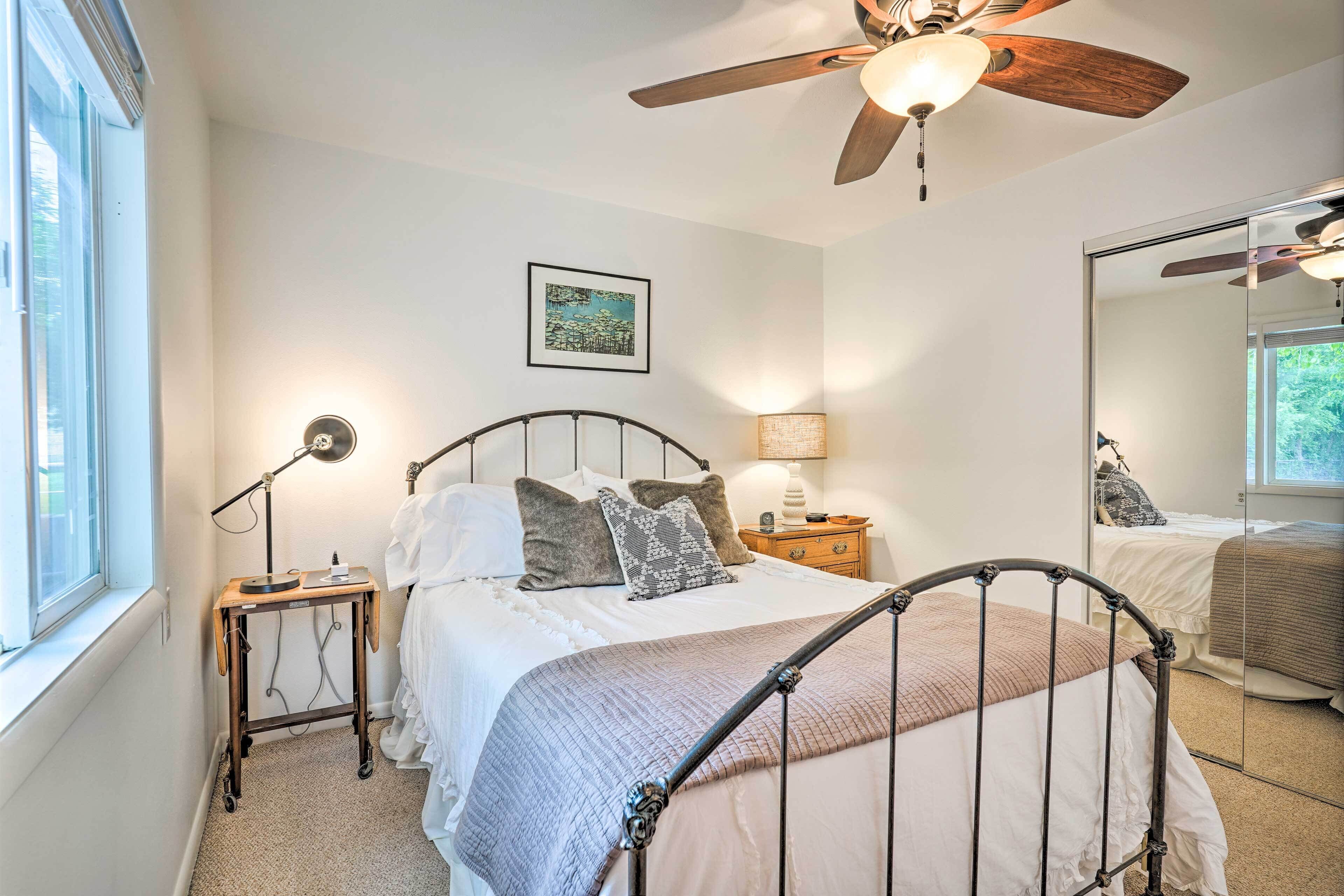 A bedroom with a bed, bedside table, lamp, and a ceiling fan.