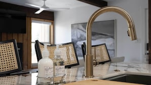 Eine Küche mit einem goldenen Wasserhahn, einer Marmorarbeitsplatte und gerahmten Kunstwerken an der Wand.