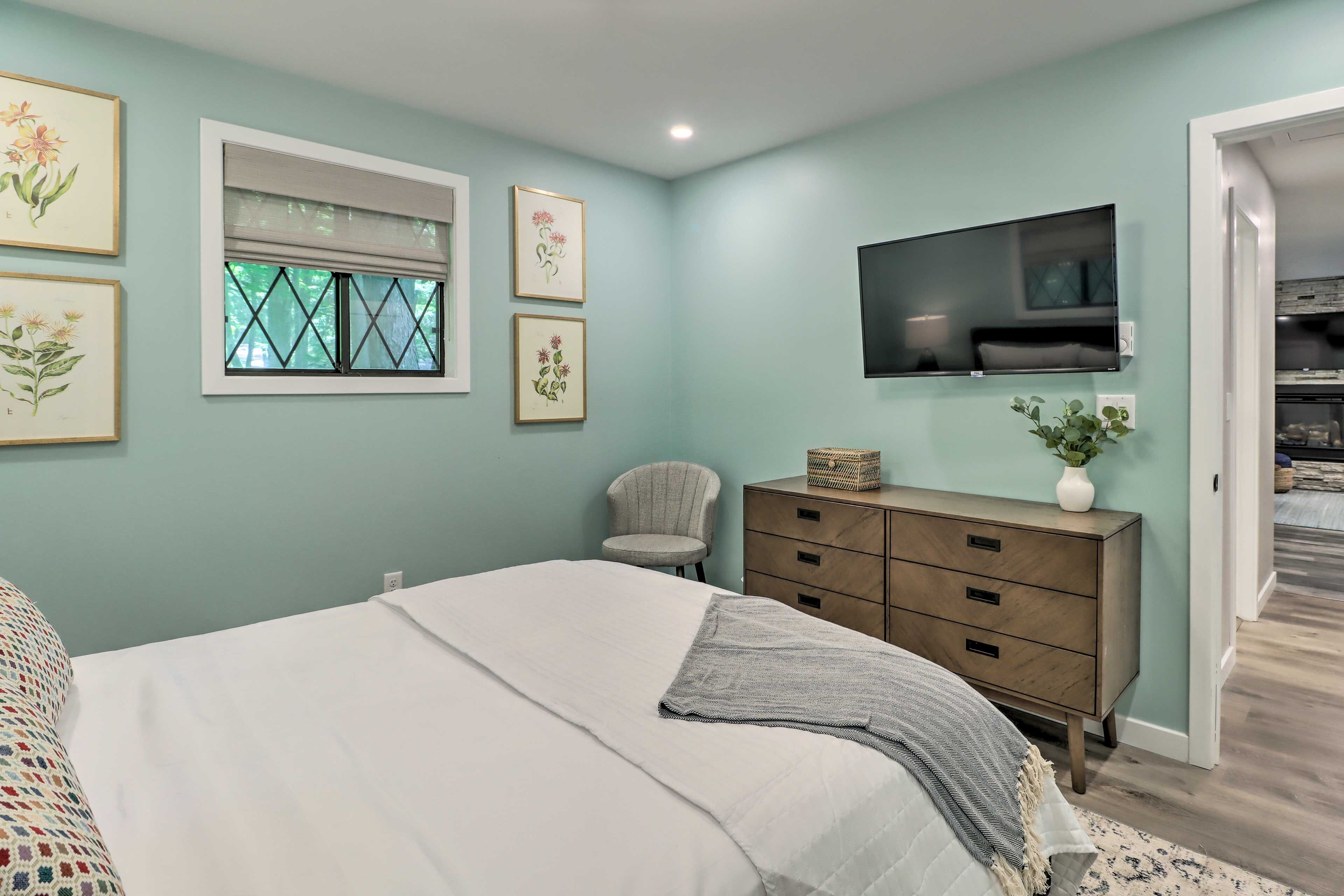 Un dormitorio con cama, cómoda, silla y una obra de arte en la pared.