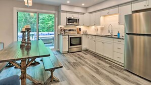 Une cuisine moderne avec des meubles blancs, des appareils en acier inoxydable et une table à manger en bois.