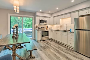 A modern kitchen with white cabinets, stainless steel appliances, and a wooden dining table.