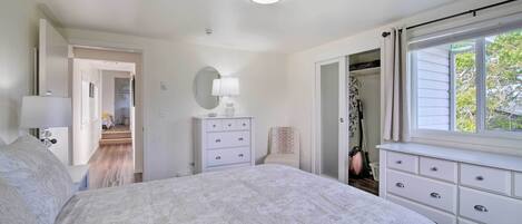 Un dormitorio con una cama grande, un aparador, un espejo y una ventana con cortinas.