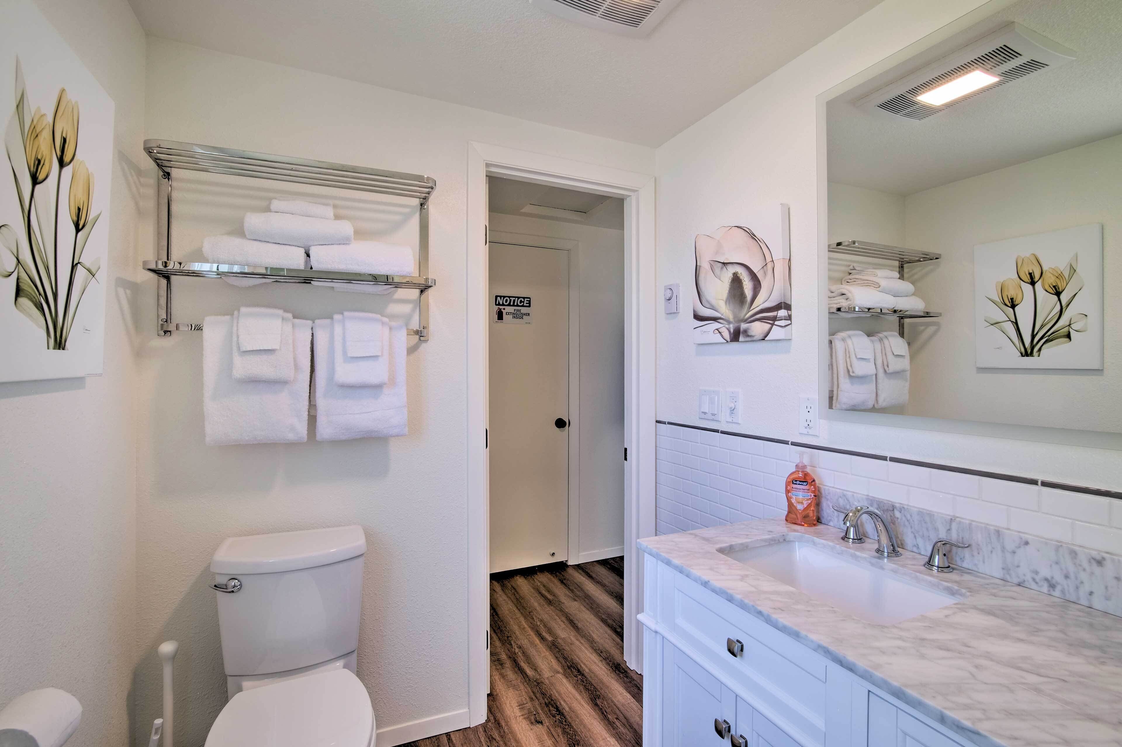 A bathroom with a toilet, a sink, a mirror, and towel racks.