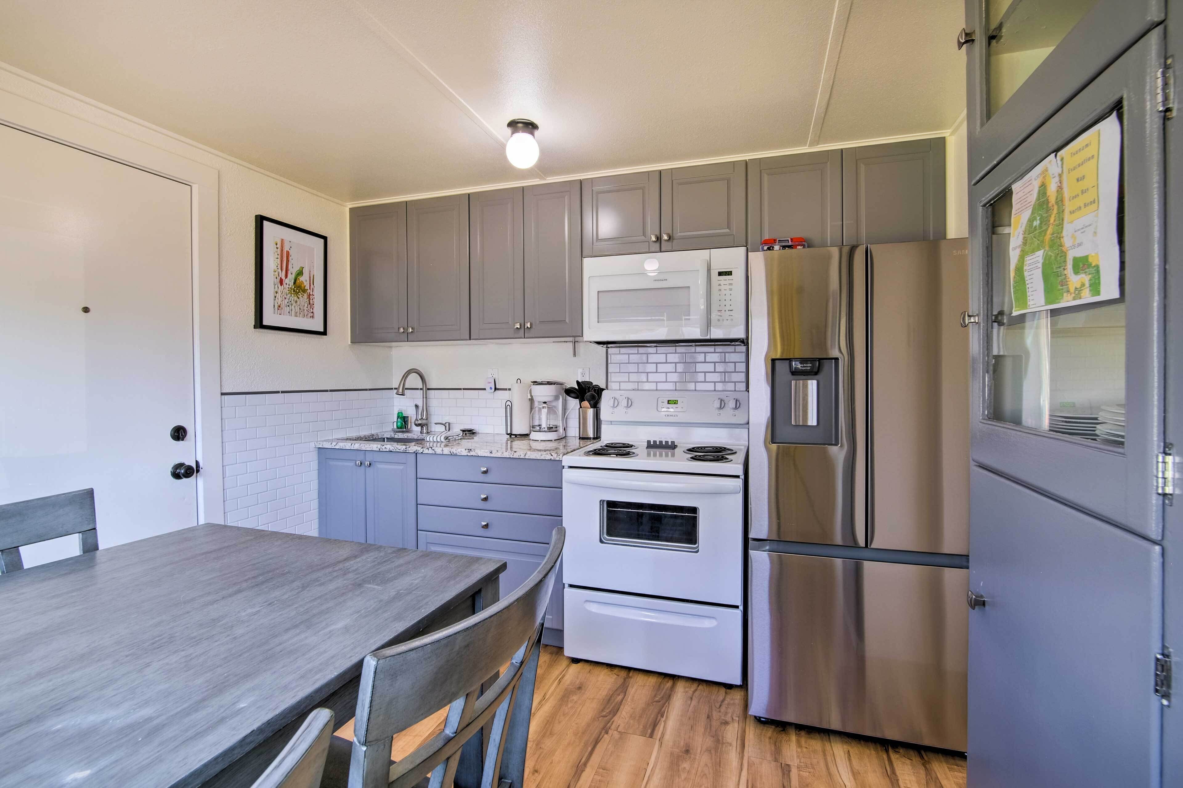 Una cocina moderna con armarios grises, una estufa blanca y un refrigerador de acero inoxidable.
