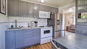 A modern kitchen with grey cabinets, a white stove, and a stainless steel refrigerator. - North Bend Home w/ Cornhole Court & Putting Green (North Bend)