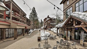 A snow-covered outdoor area with outdoor seating and a building with multiple floors and balconies. - Condo at Northstar Village - Base of Ski Resort! (Truckee)