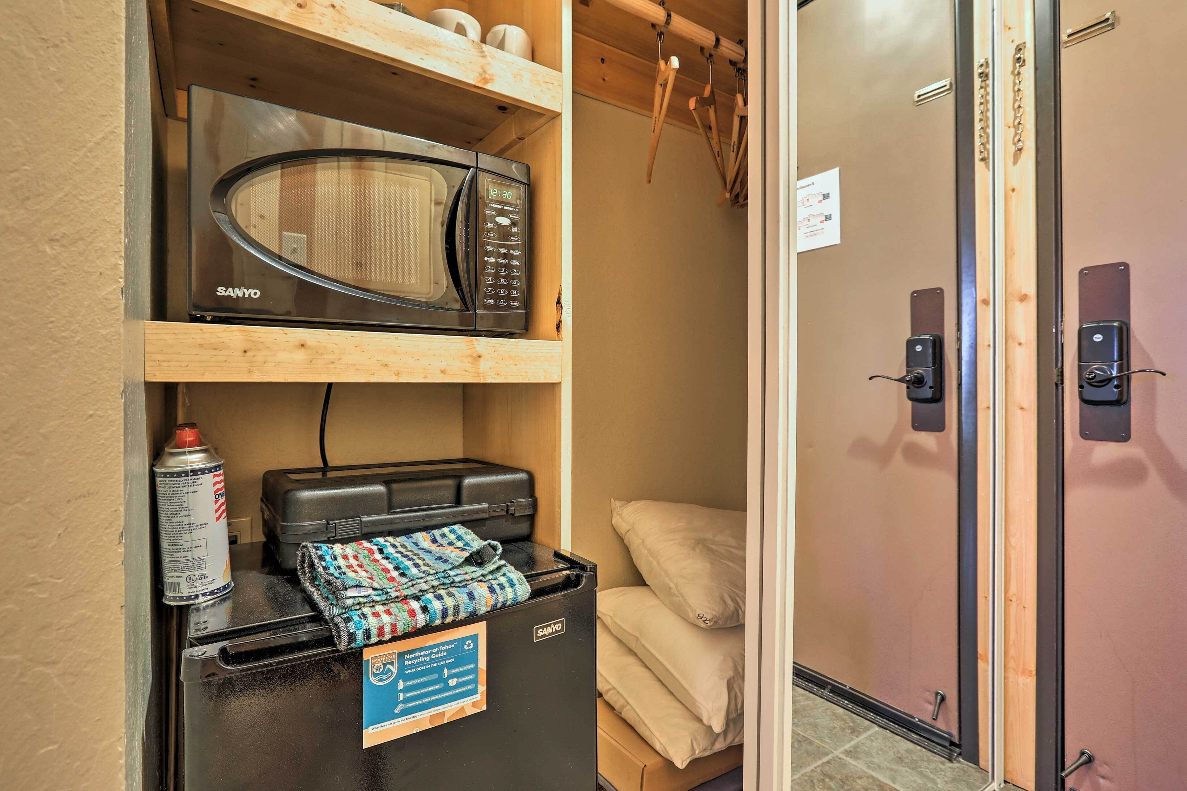 A compact kitchenette with a microwave, a small refrigerator, and a can of spray paint.