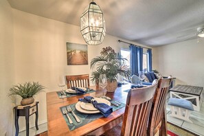 A dining area with a wooden table set for four, a hanging light fixture, and a large potted plant. - Coastal Condo w/ Dock Access, 2 Miles to Beach! (Corpus Christi)