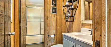 A wooden-paneled bathroom with a toilet, sink, and shower.