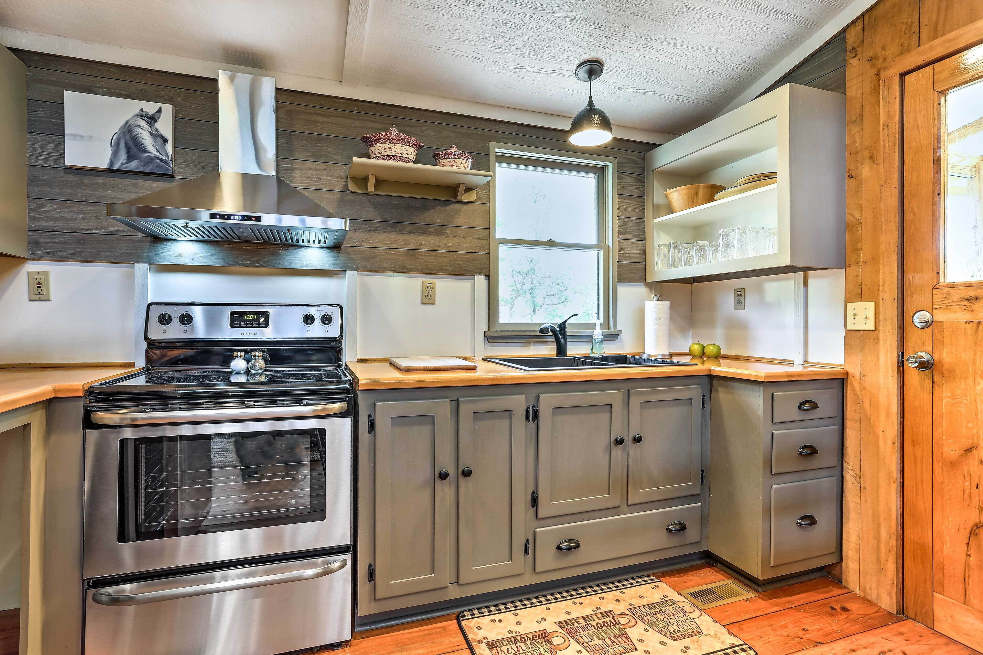 Une cuisine équipée d’une cuisinière en acier inoxydable, de meubles de rangement en bois, d’une fenêtre et d’une porte en bois.