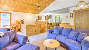 Een gezellig cabin interieur met houten plafond, een eethoek, een keuken en een woonkamer met twee banken en een kleine ronde tafel.