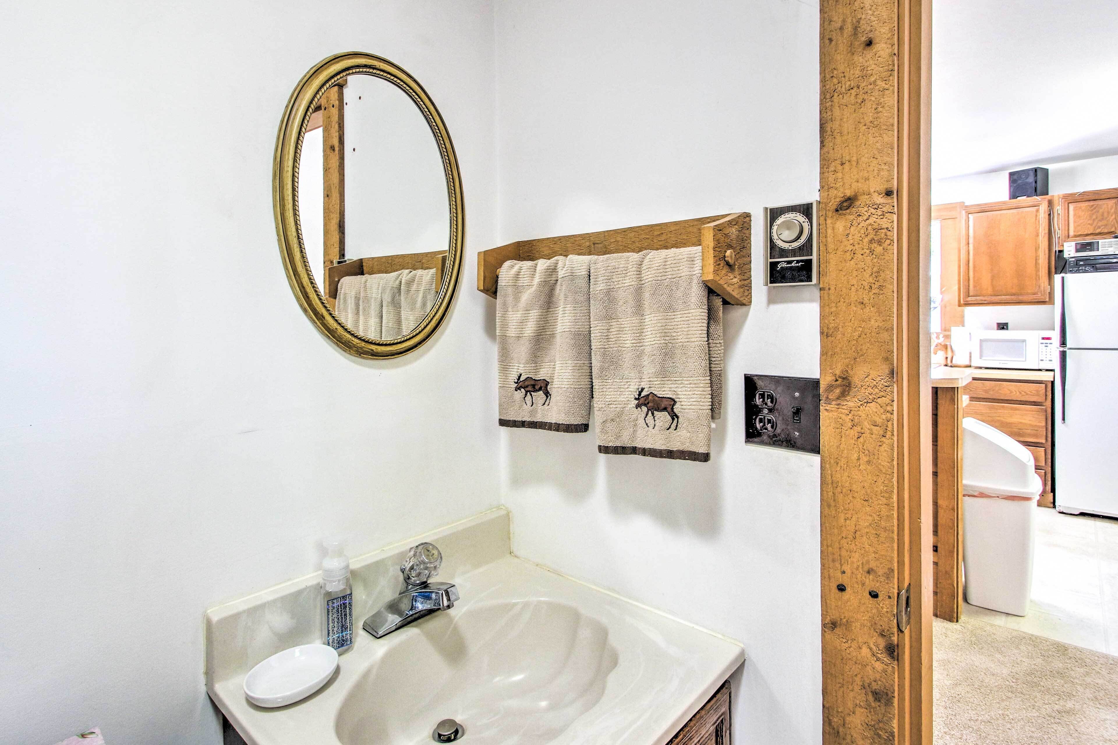 A bathroom with a sink, mirror, and towels.