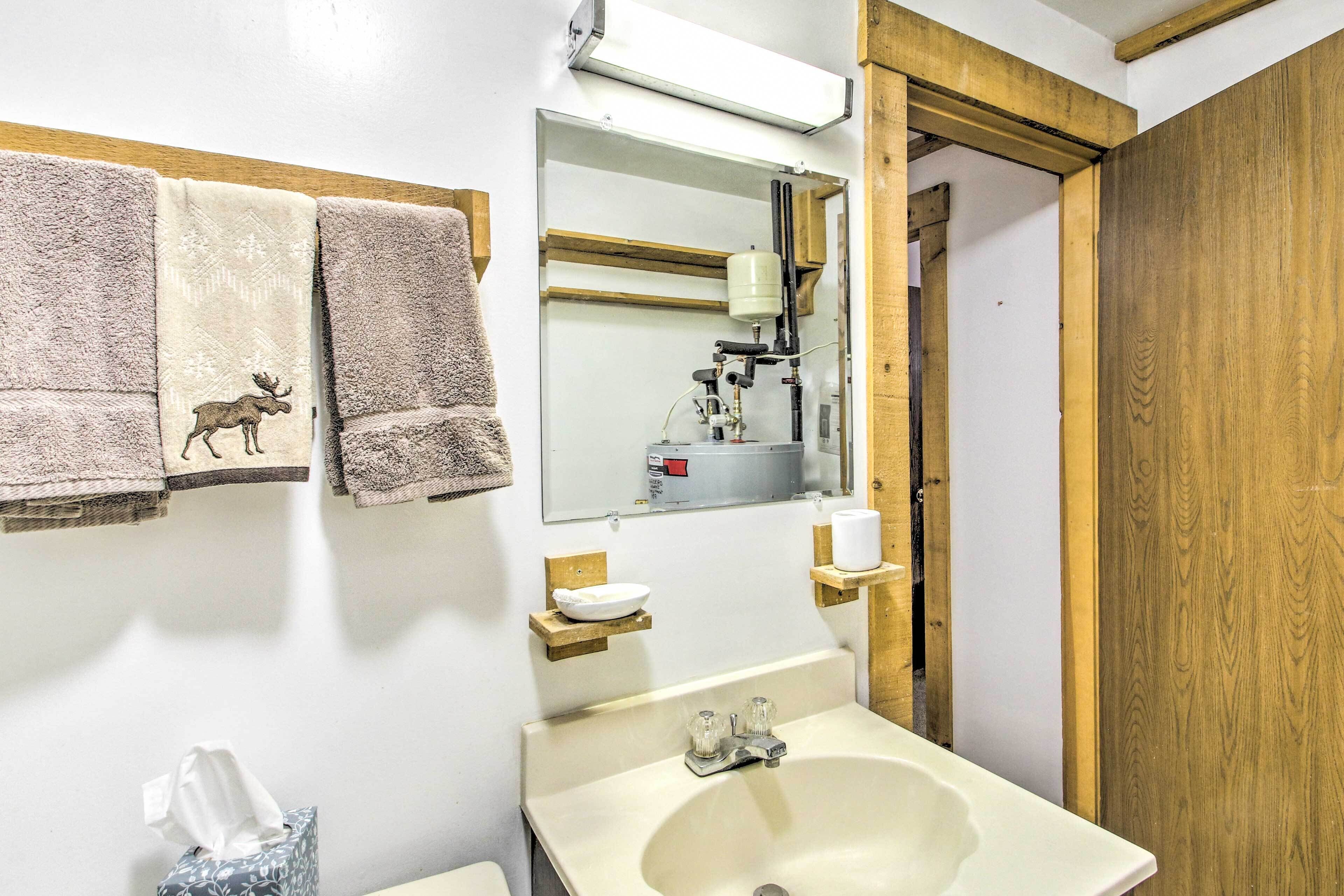 Un baño con lavamanos, espejo y toallas.