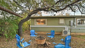 Une cabane rustique avec un foyer et quatre chaises pliantes bleues disposées autour.