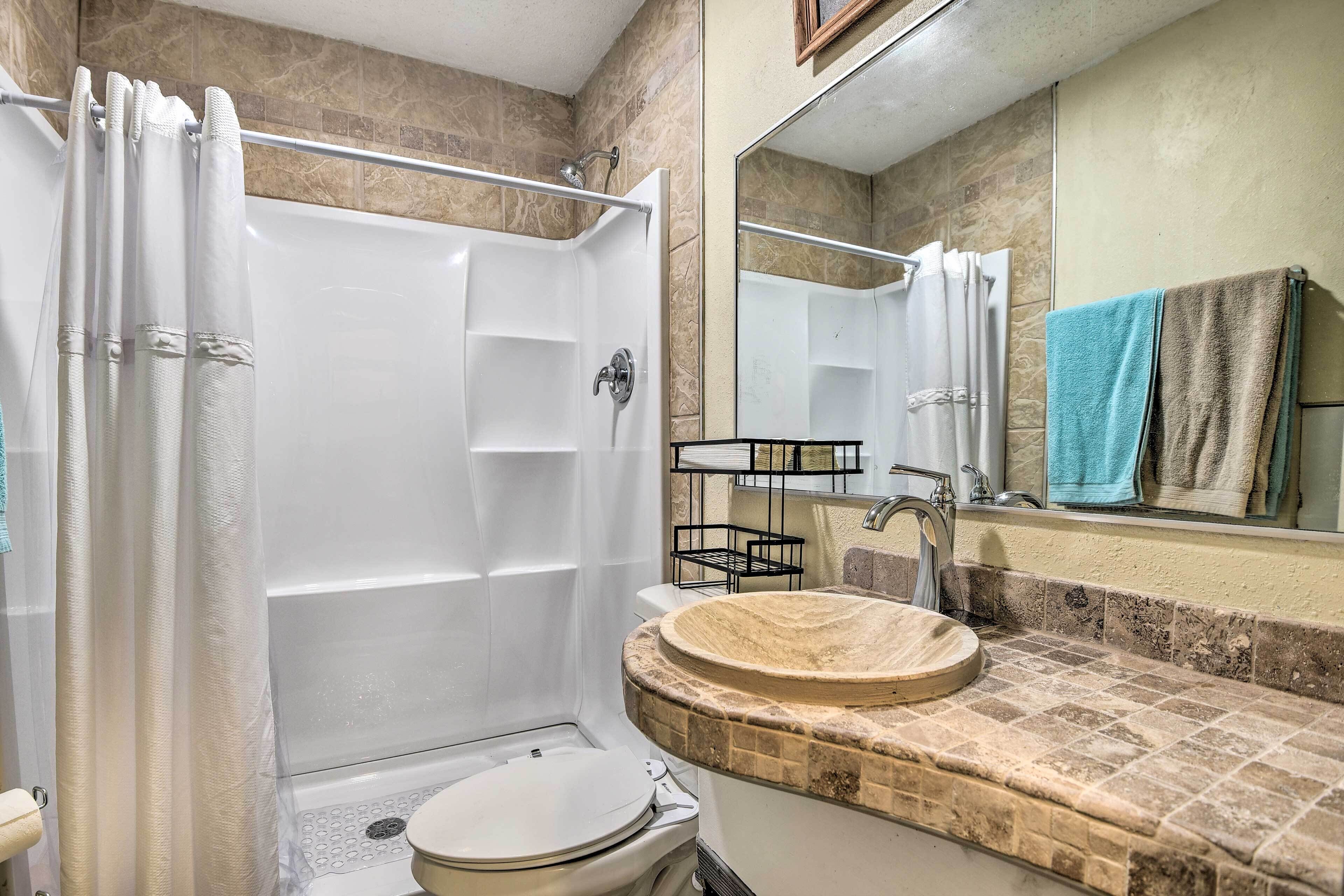 Un bagno con doccia, toilette, lavandino e specchio.