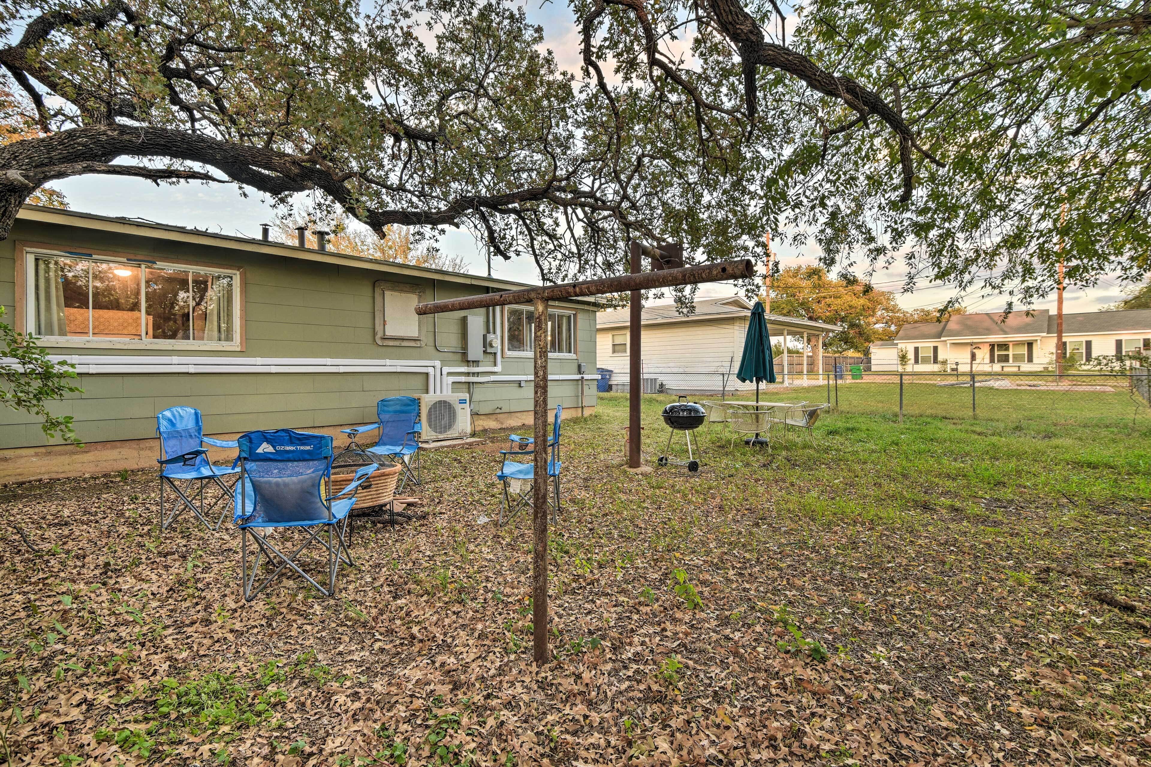 A residential backyard with a covered patio area, outdoor seating, and a barbecue grill.