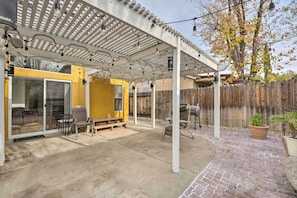 A covered patio area with a pergola, outdoor furniture, and a wooden fence.