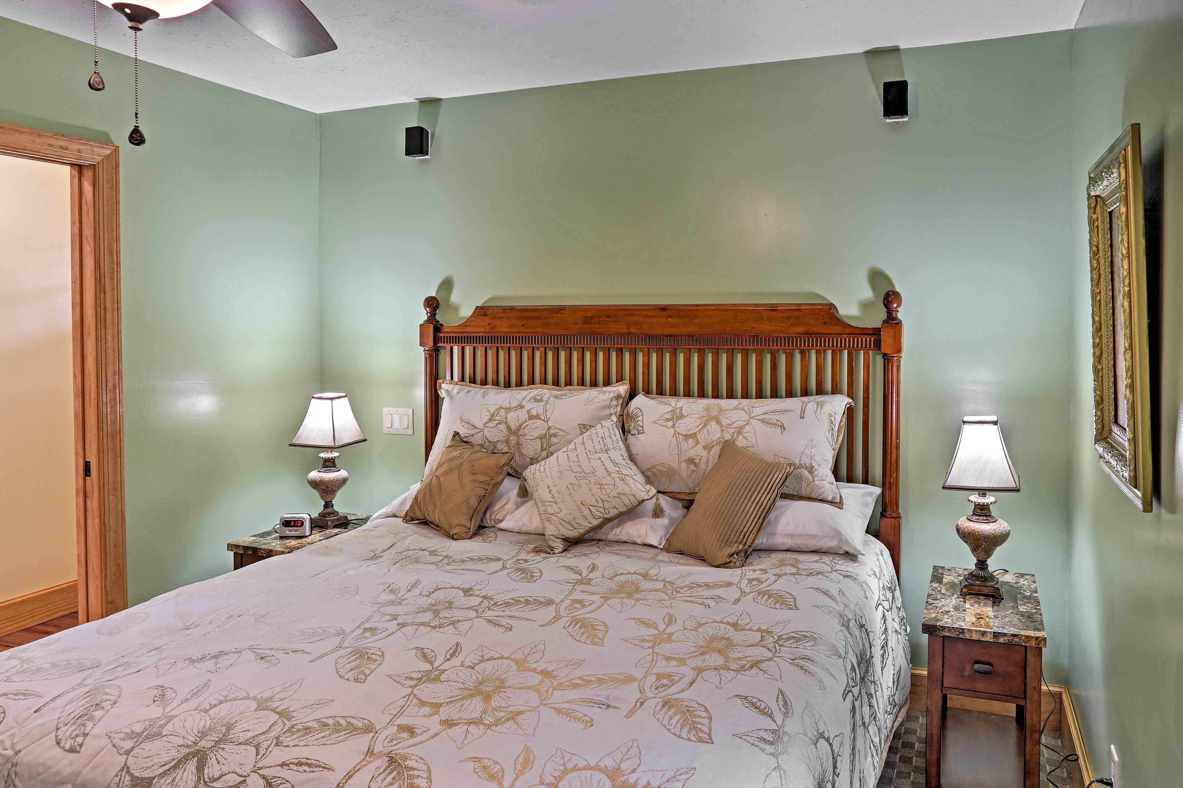A bedroom with a floral bedspread, wooden headboard, two bedside tables with lamps, and a framed picture on the wall.