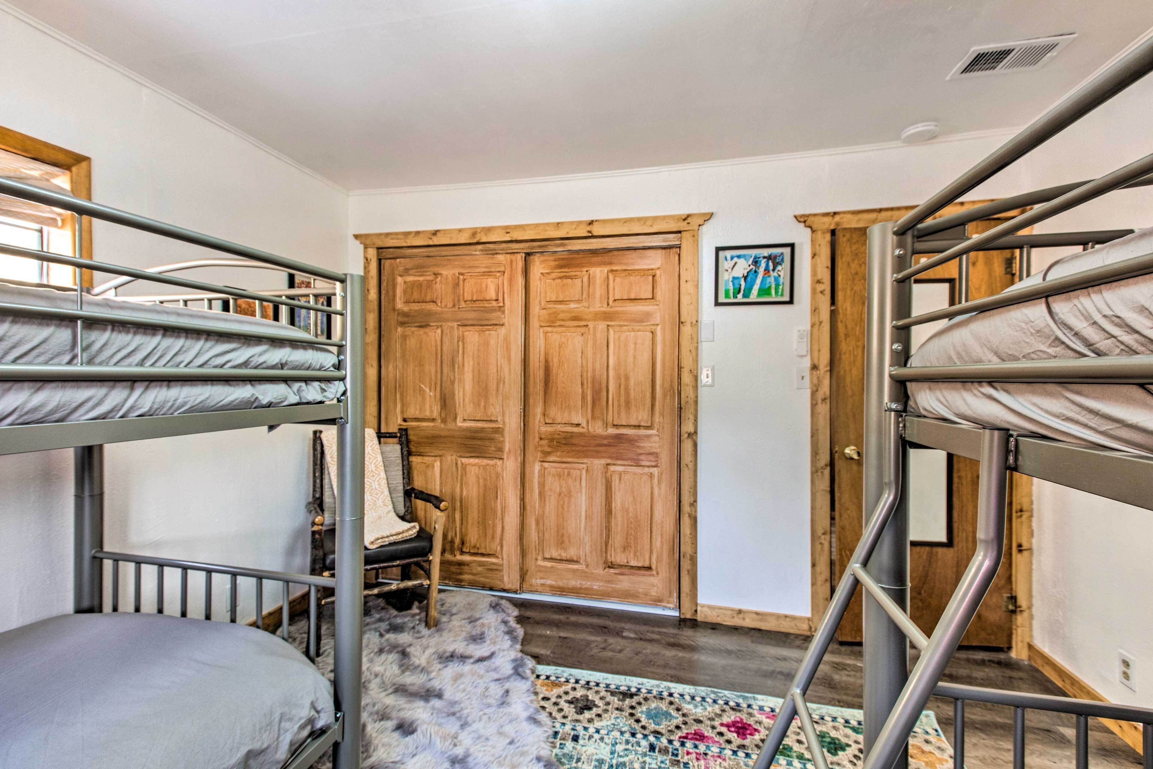 Habitación con literas, una puerta de madera y una alfombra colorida.