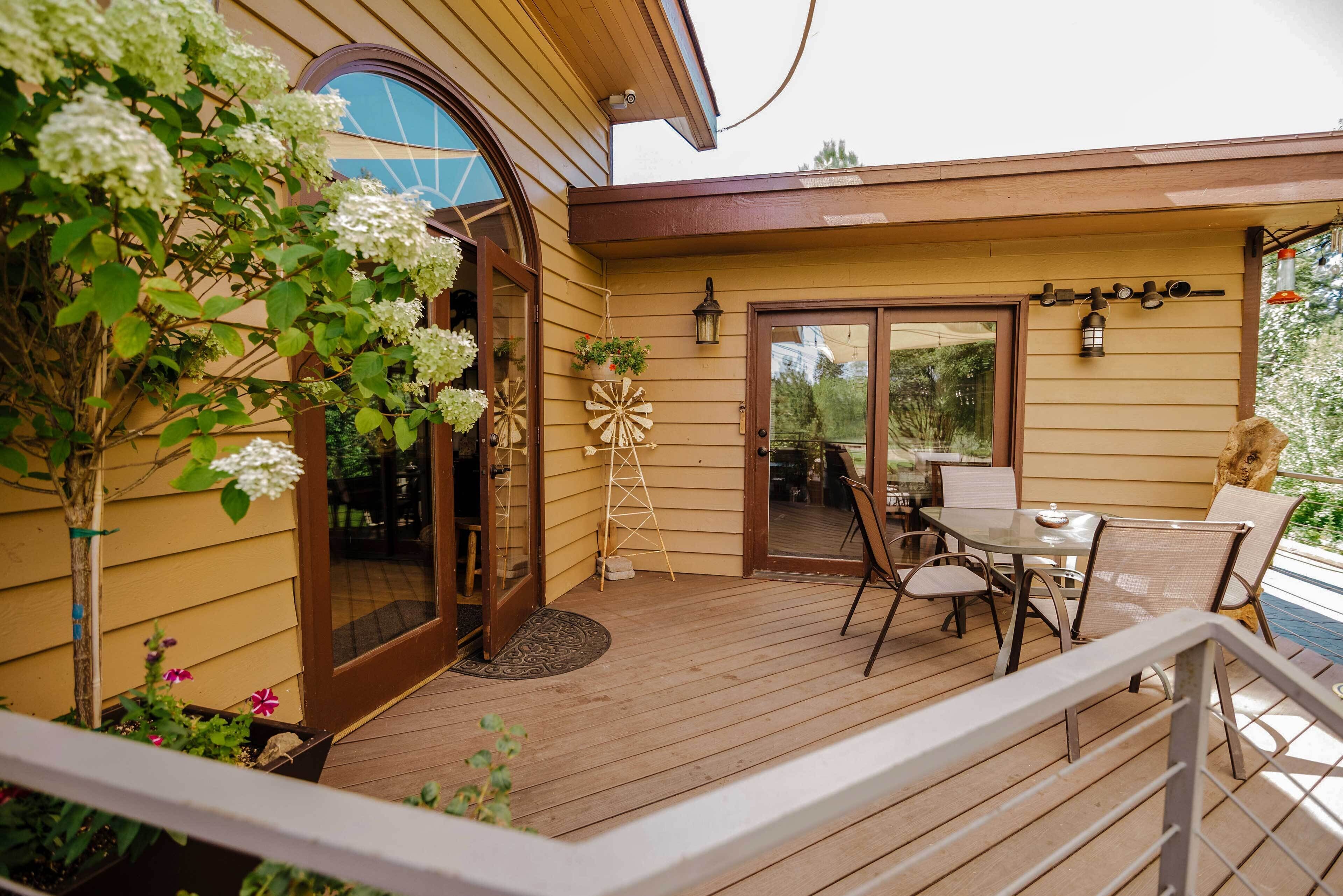A wooden deck with a glass door leading to a covered patio area.