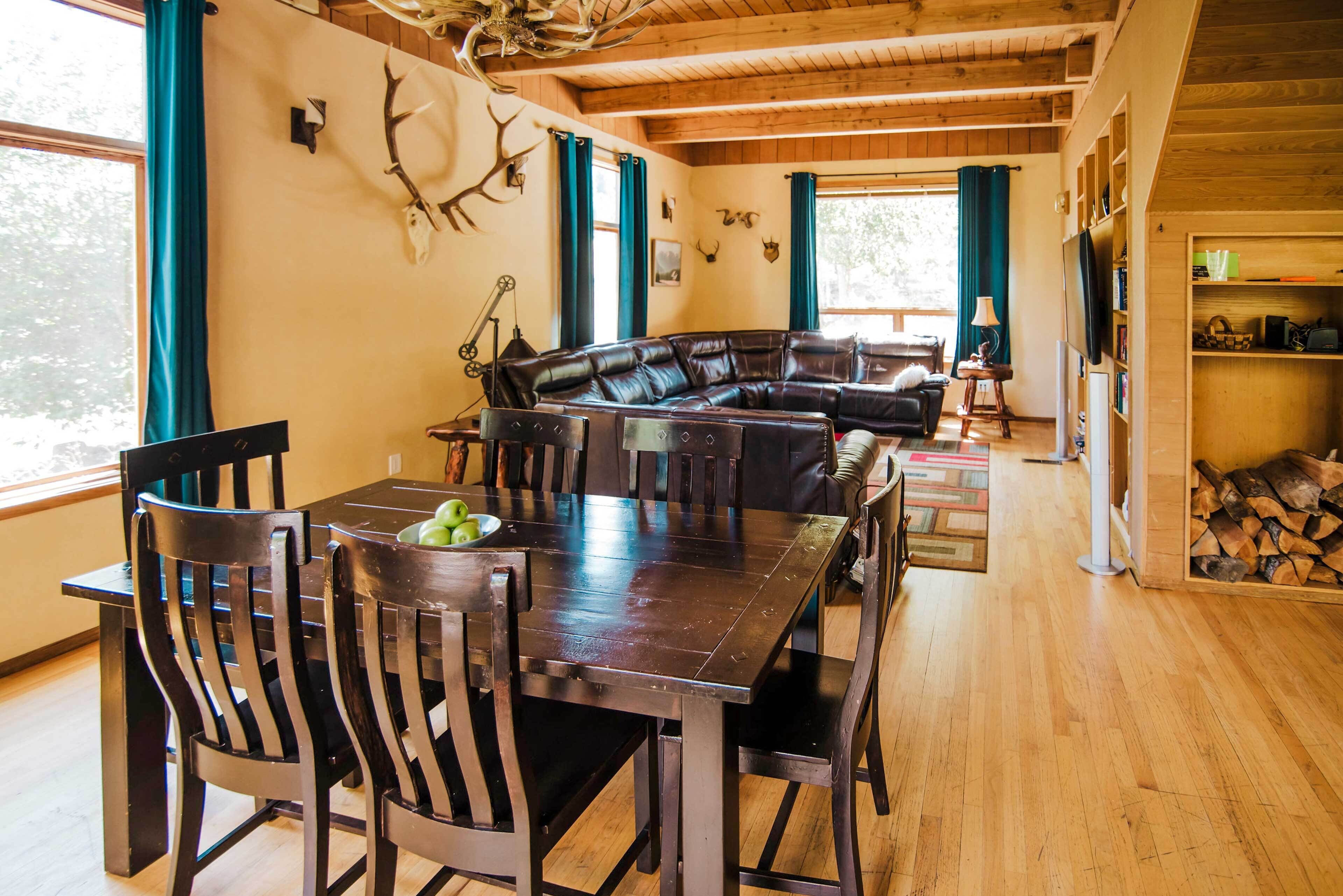 Un vaste espace de vie comprenant une table à manger en bois foncé, un canapé en cuir et une cheminée.