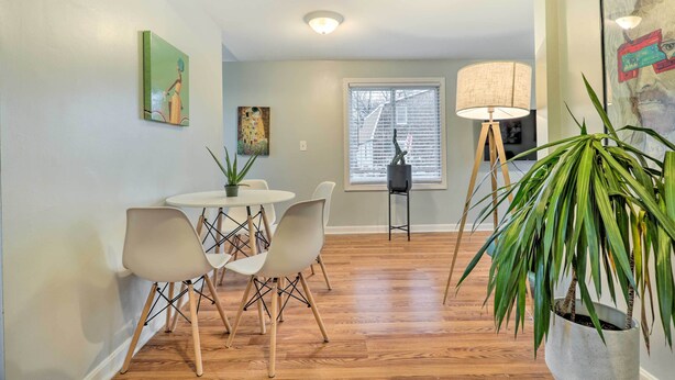 A dining area with a round table, white chairs, and a potted plant.