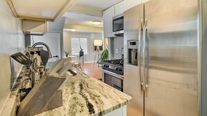 A modern kitchen with stainless steel appliances, a granite countertop, and a view into the living area.