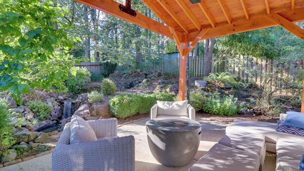 A covered patio area with wicker furniture and a stone water feature. - Beautiful Pet-friendly Washougal Home w/ Fire Pit! (Washougal)