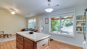 A spacious kitchen with wooden cabinets, a white countertop, and a large window providing a view of the outdoors. - Beautiful Pet-friendly Washougal Home w/ Fire Pit! (Washougal)
