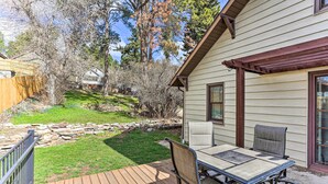 Une terrasse en bois avec une table et des chaises, un mur de pierre et une maison en arrière-plan.
