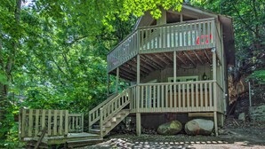 A multi-level wooden cabin with a staircase, surrounded by dense forest. - Rustic Gatlinburg Chalet w/ Hot Tub: 2 Mi to Town (Gatlinburg)