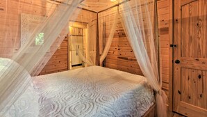 A wooden room with a bed, a wardrobe, and a door. - Rustic Gatlinburg Chalet w/ Hot Tub: 2 Mi to Town (Gatlinburg)