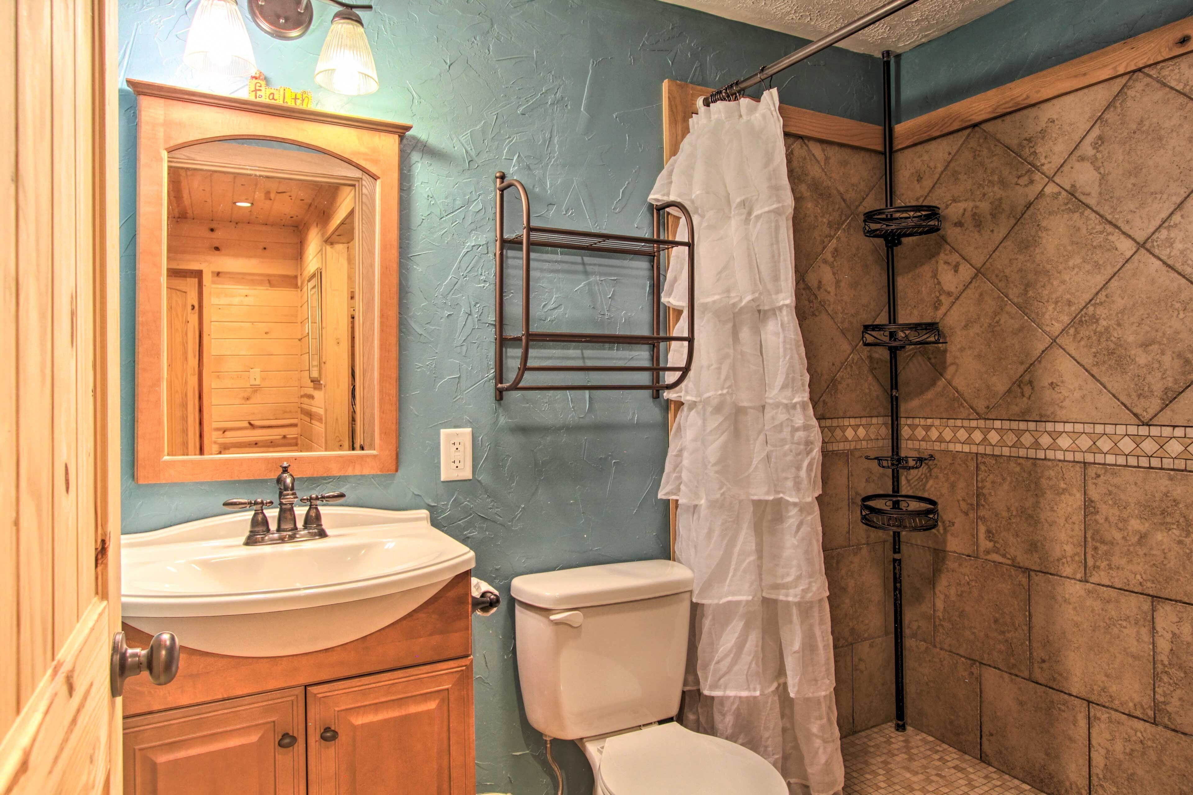 Ein Badezimmer mit einem Holzbadezimmer-Möbel, einem weißen Waschbecken, einer Toilette und einer Dusche mit weißem Duschvorhang.
