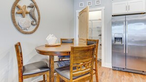 A dining area with a wooden table and chairs, a refrigerator, and a wall decoration.