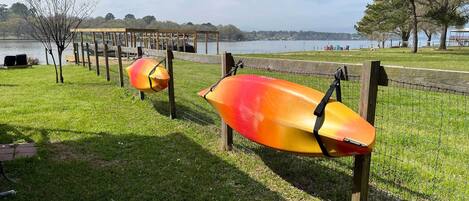 A grassy area with two lifebuoys hanging on a fence near a body of water.