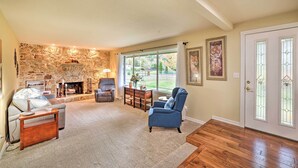 A living room with a stone fireplace, a sofa, a blue armchair, and a dining table.