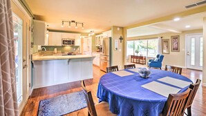 A spacious kitchen with a central island, dining area with a blue tablecloth, and a living room with a blue armchair.