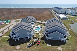 A coastal hotel with a pool, multiple balconies, and a view of the beach and ocean.