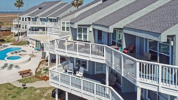 A multi-story residential building with balconies, a swimming pool, and outdoor seating areas. - Pool w/ Spa! Beachfront Condo in Port Aransas (Port Aransas)