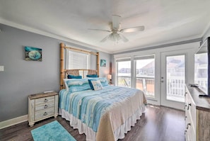 A bedroom with a bed, a nightstand, a dresser, a ceiling fan, and a view through the door.
